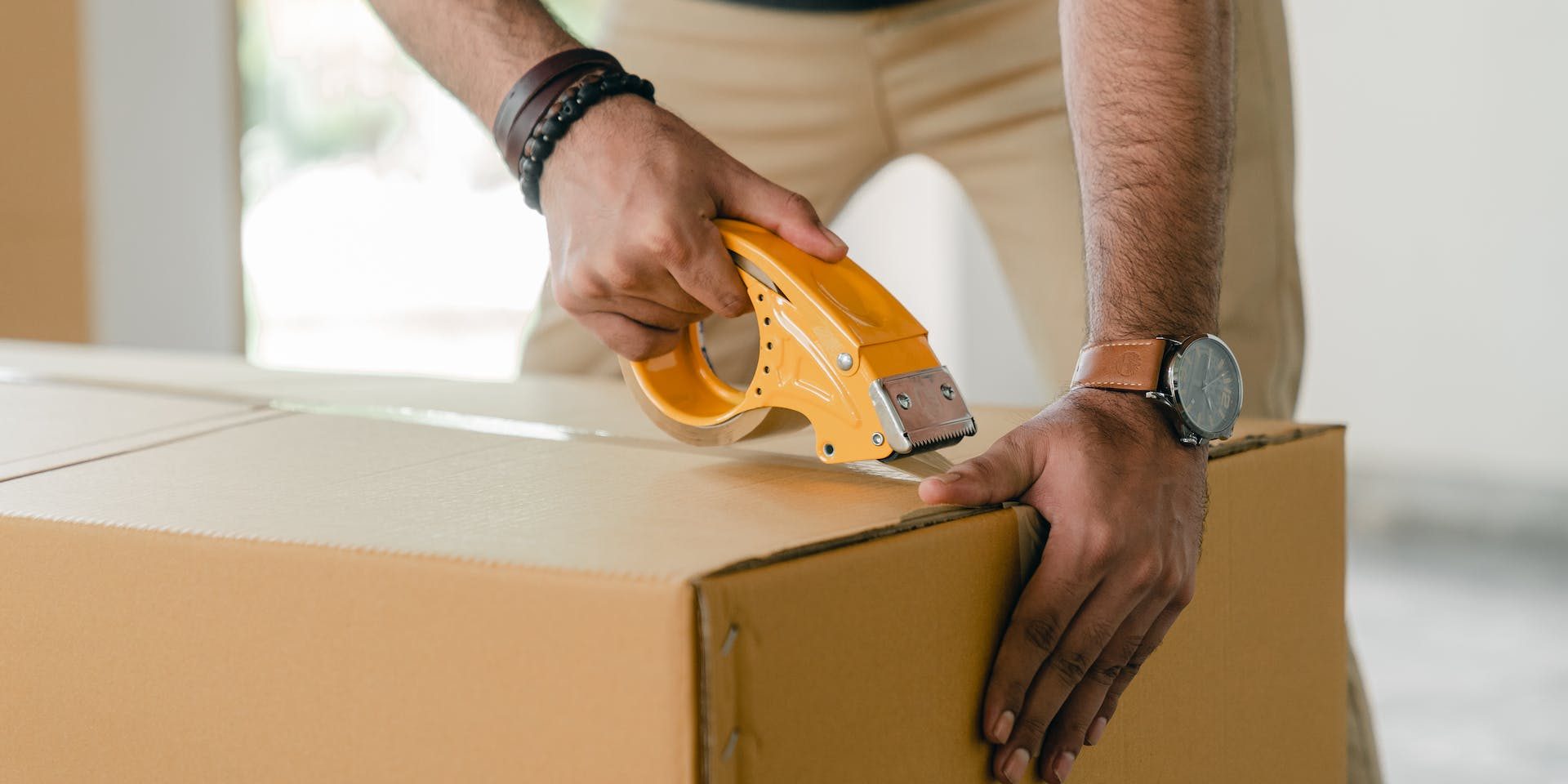 A man using a box cutter to open a cardboard box.